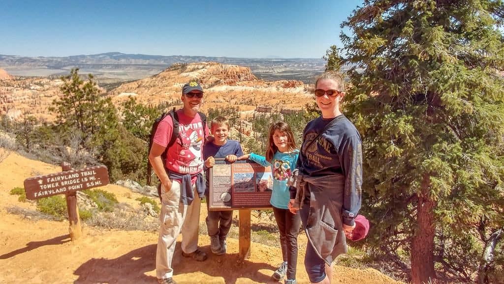 Mom, dad and two kids standing at a national park sign inside Bryce Canyon National Park