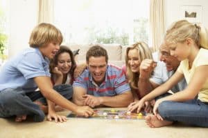 An entire family laying on the floor playing a board game