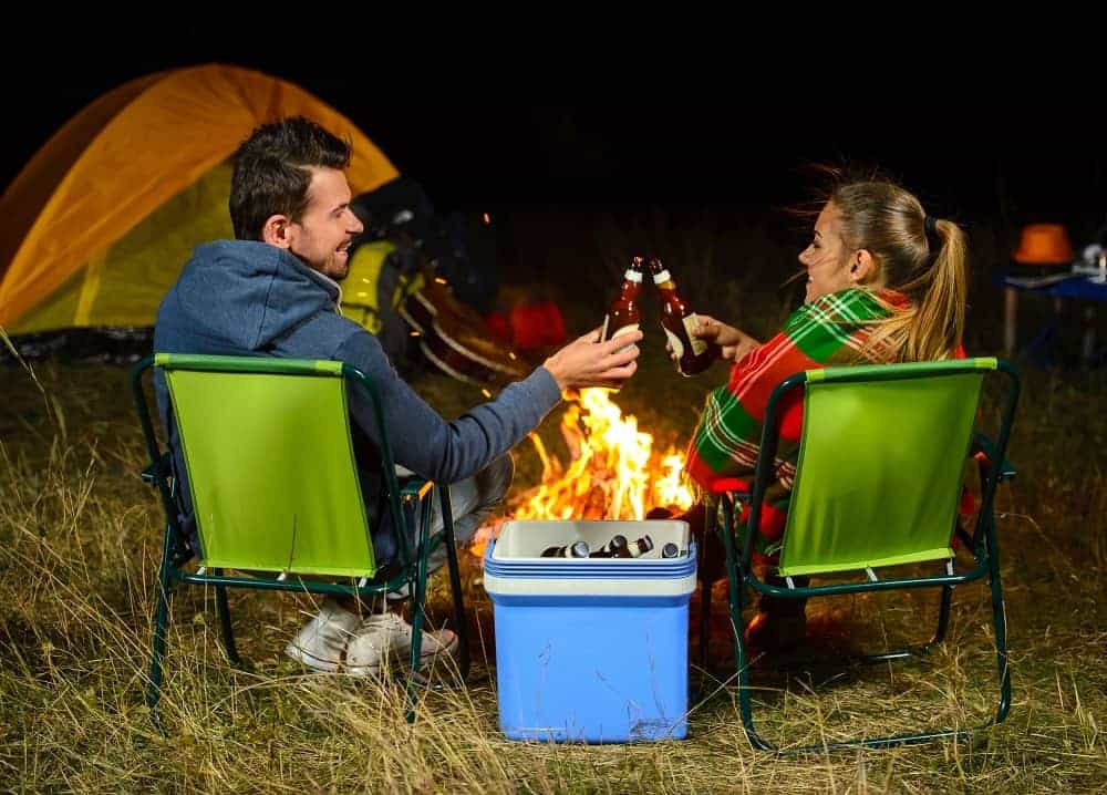 A couple enjoying an awesome Valentines Day sitting by a campfire enjoying a beer together