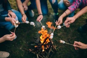 A group of people huddled over their fire using their family camping checklist