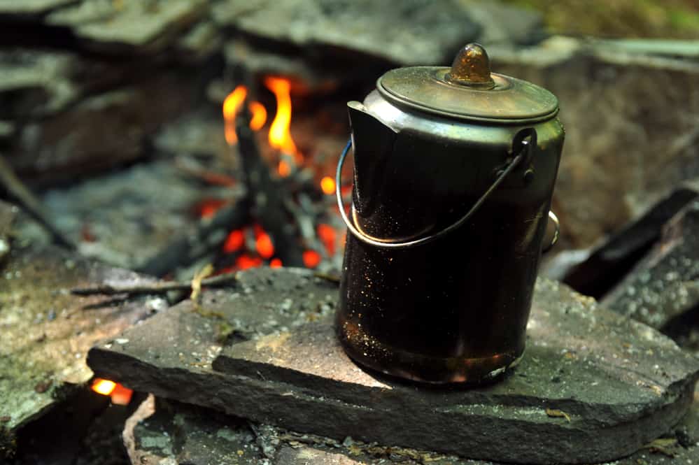 Coffee brewing over camping fire for breakfast