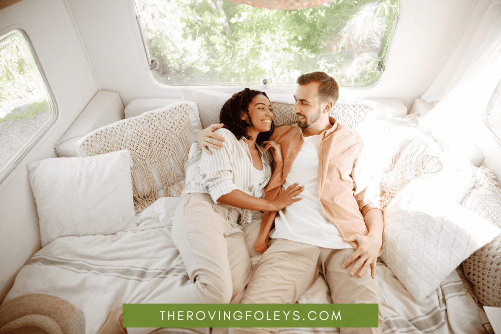 couple laying on RV bed with white rv bedding