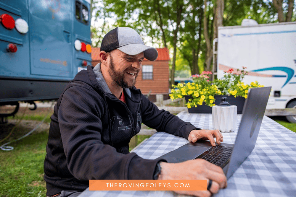 man working on computer outside RV