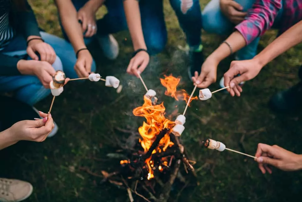 A group of people huddled over their fire using their family camping checklist